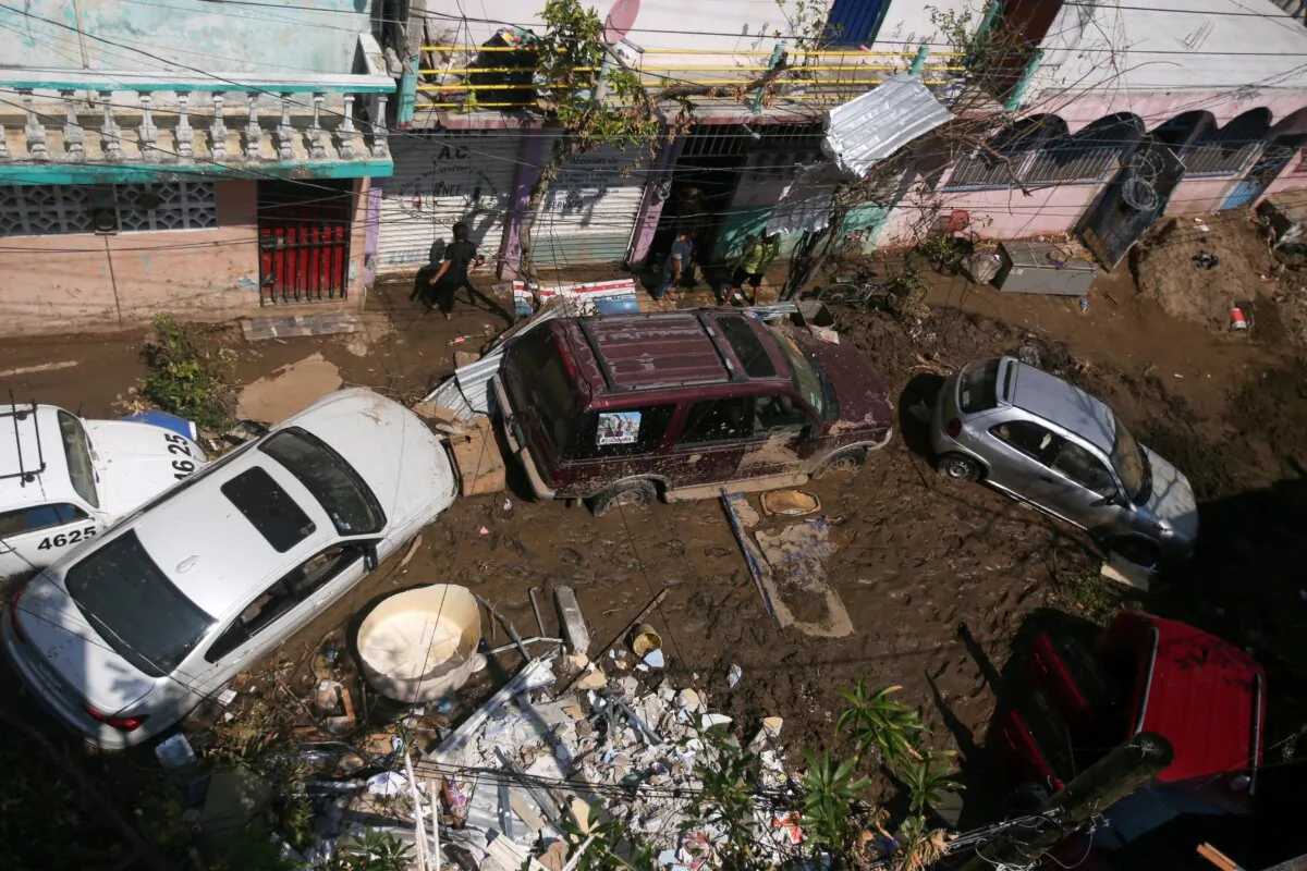 People stand amidst damaged items and debris in the mud, in the aftermath of Hurricane Otis, in the Progreso neighborhood in Acapulco, Mexico, on Oct. 30, 2023. (Quetzalli Nicte-Ha/Reuters)