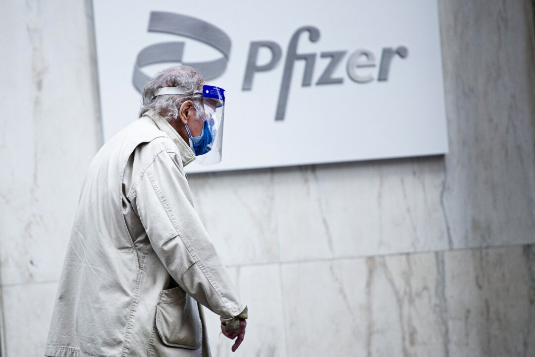 A man wearing facemask and shield walks past the Pfizer headquarters in New York, on March 11, 2021. (Kena Betancur/AFP/Getty Images)