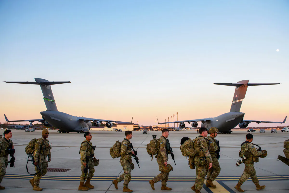 Soldiers with the 82nd Airborne division walk across the tarmac at Green Ramp to deploy to Poland at Fort Bragg, Fayetteville, N.C., on Feb. 14, 2022. (Melissa Sue Gerrits/Getty Images)