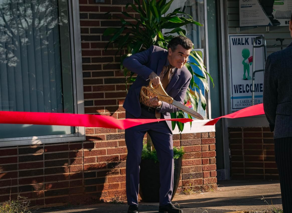 man cuts ribbon in PAIN HUSTLERS