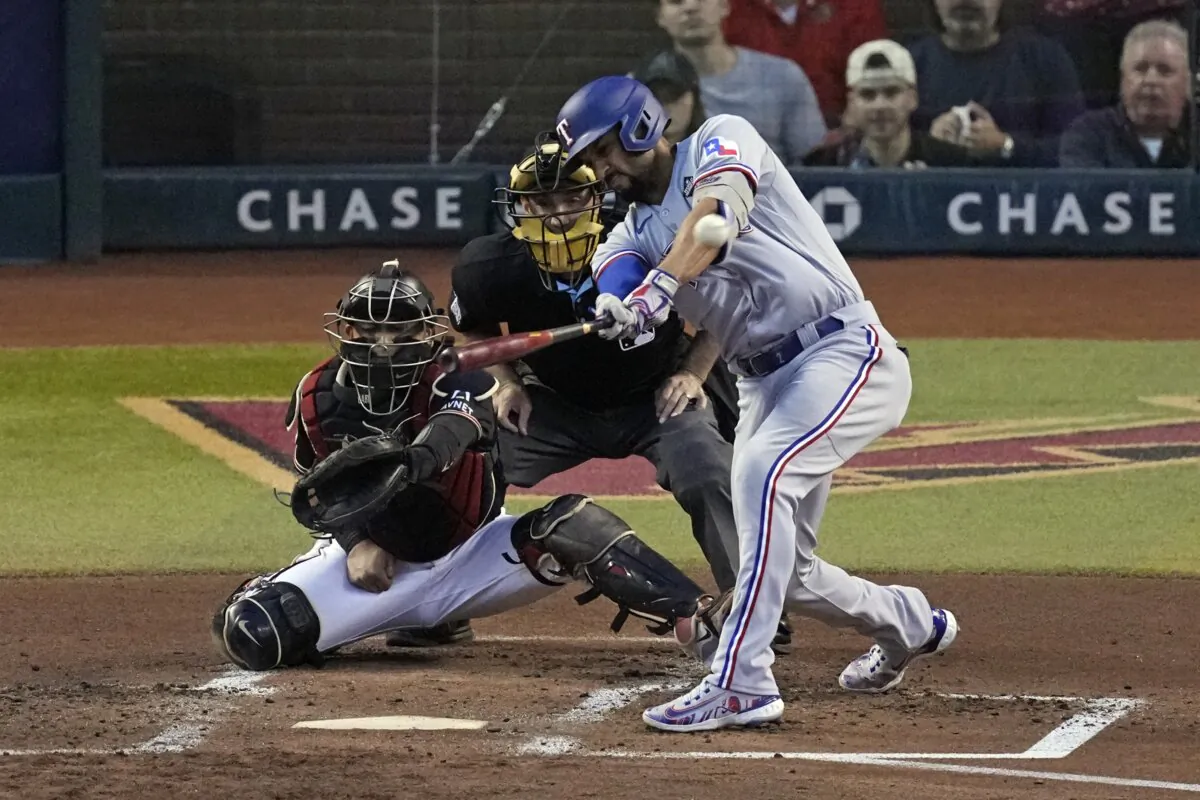 Texas Rangers' Marcus Semien (R) hits a two-run triple as Arizona Diamondbacks catcher Gabriel Moreno reaches for the pitch during the second inning in Game 4 of the baseball World Series in Phoenix on Oct. 31, 2023. (Ross D. Franklin/AP Photo)