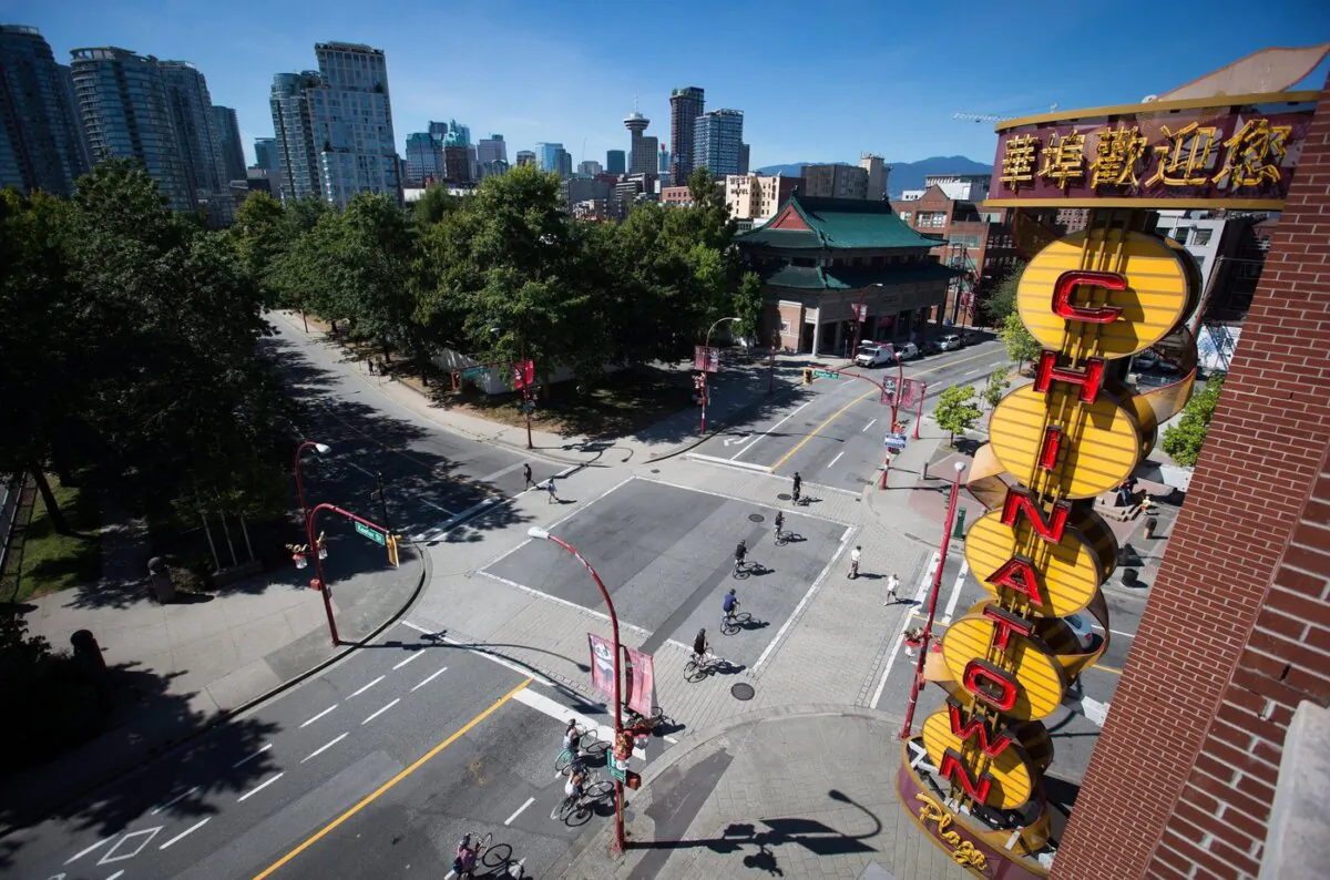 Cyclists ride past a neon Chinatown sign in Vancouver, B.C., on Aug. 18, 2016. (The Canadian Press/Darryl Dyck)