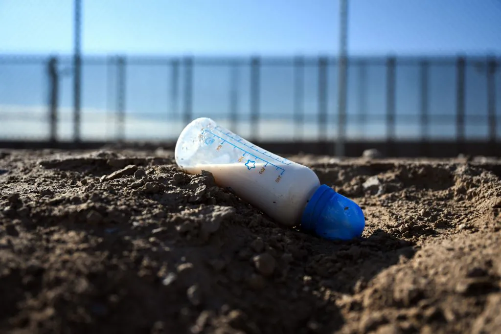 A baby milk formula bottle rests alongside a canal along the US-Mexico border wall in El Paso, Texas, on December 19, 2022. (Photo by PATRICK T. FALLON/AFP via Getty Images)