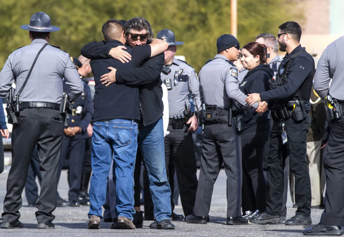 Nevada State Police and other law enforcement officers embrace in the parking lot after the body of a state trooper was taken into the Clark County Coroner's Office in Las Vegas on Nov. 30, 2023. (Steve Marcus/Las Vegas Sun via AP)
