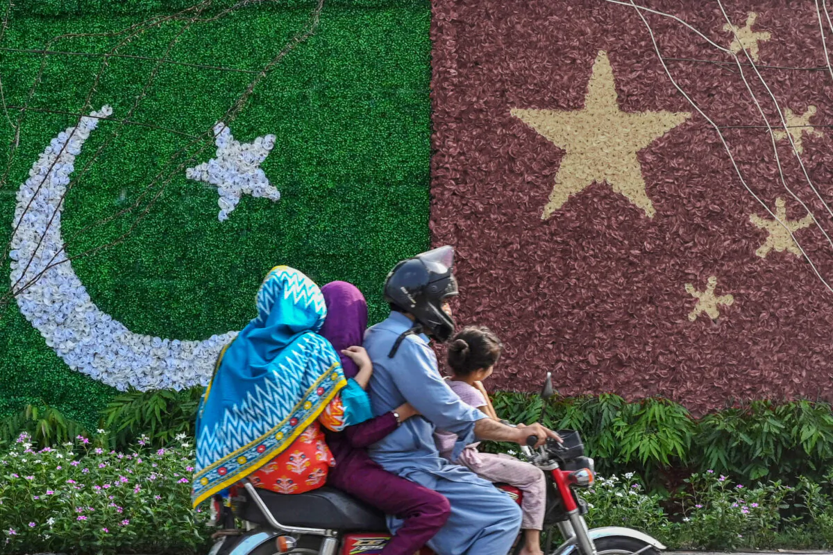 A family rides past a decoration depicting the flags of China and Pakistan ahead of the visit of Chinese Vice Premier He Lifeng, in Lahore, Pakistan, on July 30, 2023. (Arif Ali/AFP via Getty Images)