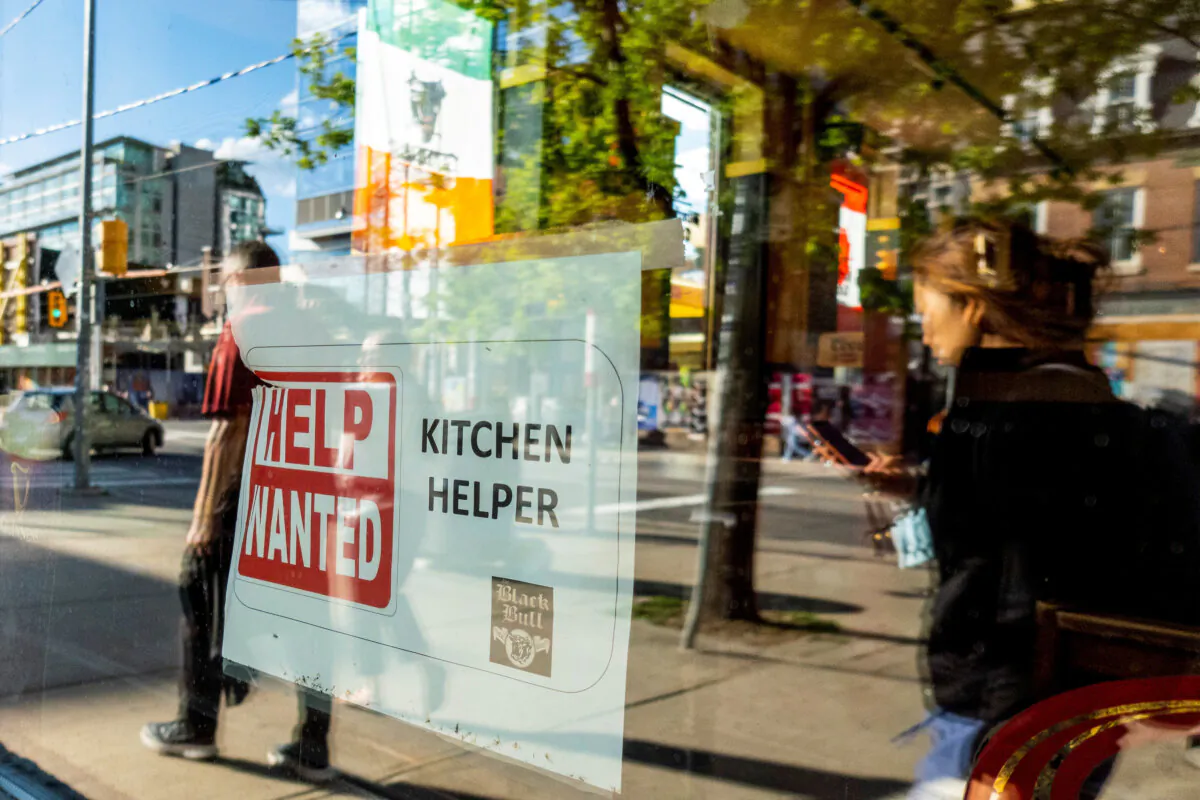 A help wanted sign hangs in a bar window along Queen Street West in Toronto on June 10, 2022. (Reuters/Carlos Osorio)