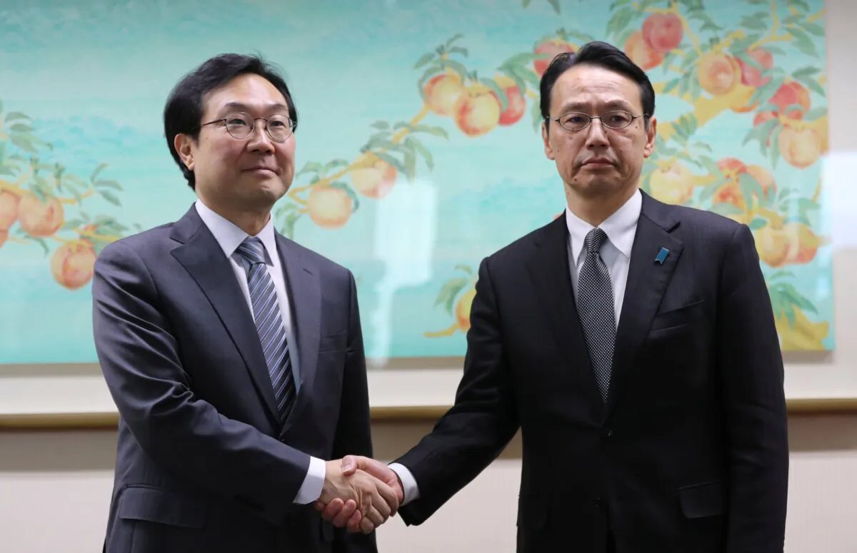 South Korea's Special Representative for Korean Peninsula Peace and Security Affairs Lee Do-hoon (L) and Japan's director general of the Asian and Oceanian Affairs Bureau Kenji Kanasugi shake hands for the media before their meeting at the Foreign Ministry in Seoul on Jan. 8, 2018. (Lee Jin-man /AFP via Getty Images)
