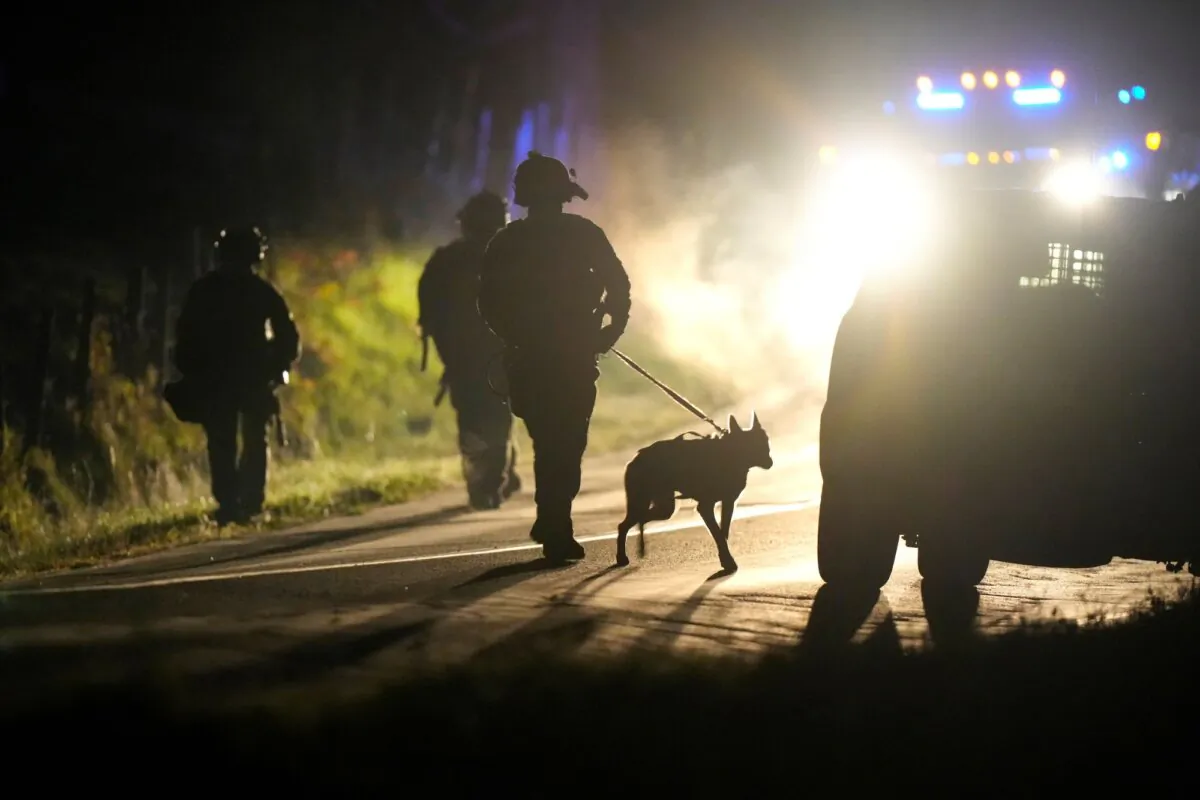 A member of law enforcement walks with a police dog outside a property on Meadow Road in Bowdoin, Maine, on Oct. 26, 2023. (Steven Senne/AP)