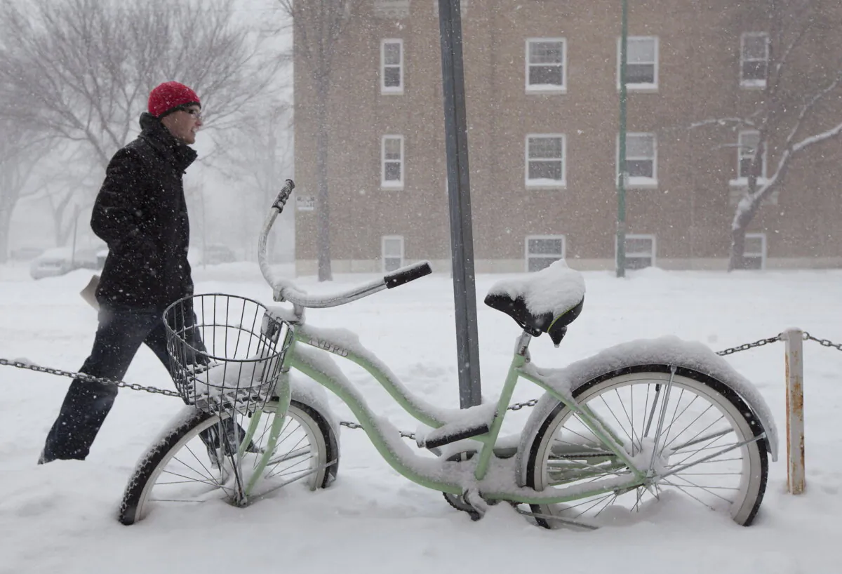 A man walks past a snow-covered bike and a residential building in Saskatoon in a file photo. (The Canadian Press/Jonathan Hayward)