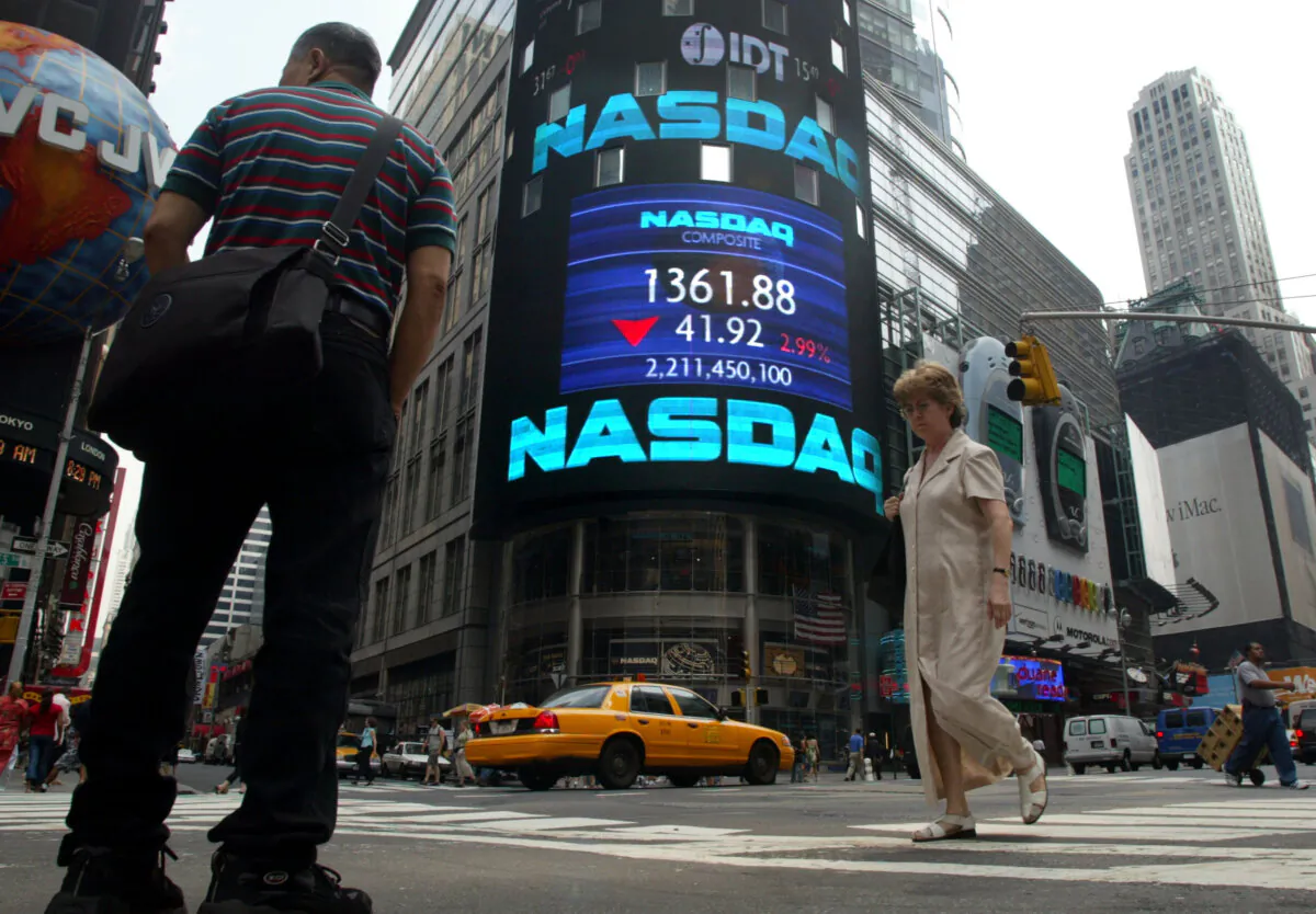 Pedestrians walk past the NASDAQ headquarters in New York, with the NASDAQ composite index at another five-year low, on July 2, 2002. (Mario Tama/Getty Images)