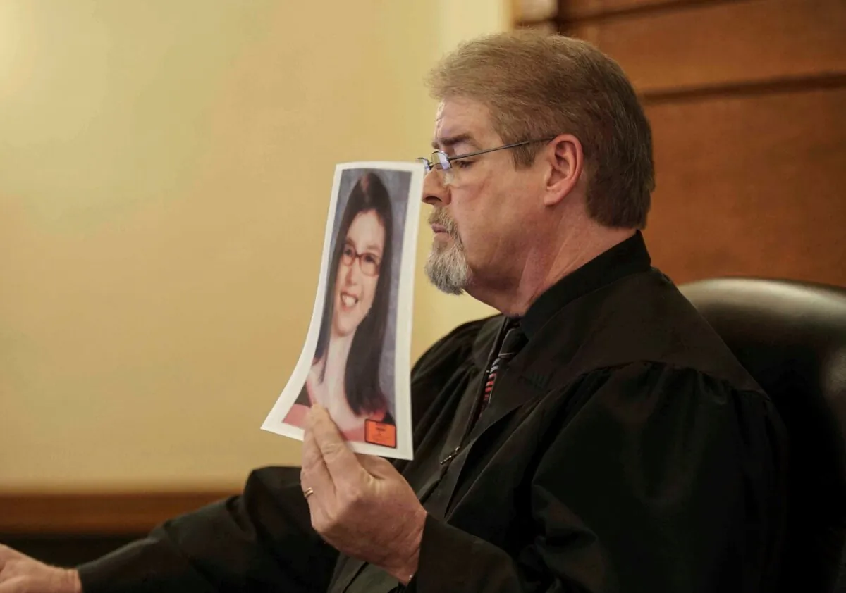 Judge Terry Rickers holds up a photo of Sabrina Ray prior to handing down a sentence to her parents, Misty Jo Bousman Ray and Marc Ray, at the Dallas County Courthouse in Adel, Iowa on Jan. 18, 2019. (Bryon Houlgrave/The Des Moines Register via AP)