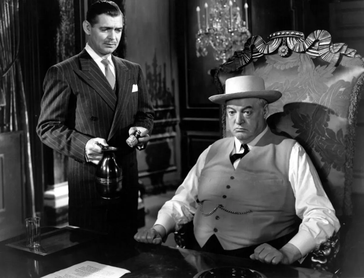 Victor “Vic” Norman (Clark Gable, L) and Evan Llewellyn Evans (Sydney Greenstreet), who might as well be sitting on a throne, in “The Hucksters” (Metro-Goldwyn-Mayer)