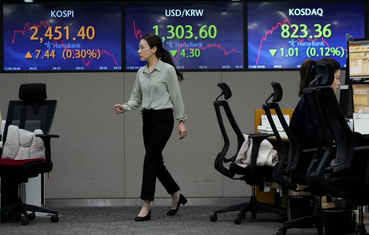 A currency trader passes by the screens showing the Korea Composite Stock Price Index (KOSPI), (L), and the foreign exchange rate between U.S. dollar and South Korean won, (C), at the foreign exchange dealing room of the KEB Hana Bank headquarters in Seoul, South Korea, on Nov. 8, 2023. (Ahn Young-joon/AP Photo)