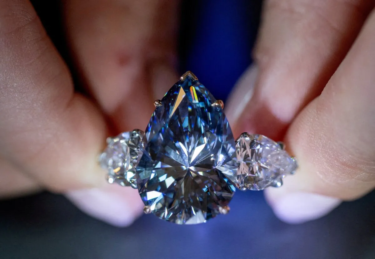 Christie’s auction house intern Carola Chiadini holds the "Bleu Royal" diamond, during an auction preview in Geneva on Nov. 1, 2023. (Denis Balibouse/Reuters)