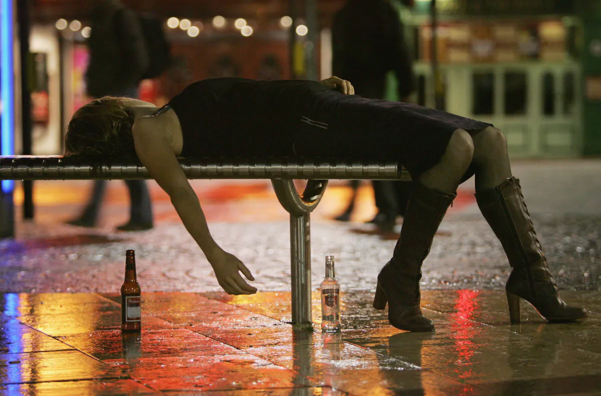 A woman lies on a bench after leaving a bar in Bristol City Centre in Bristol, England, on Oct. 15, 2005. (Matt Cardy/Getty Images)