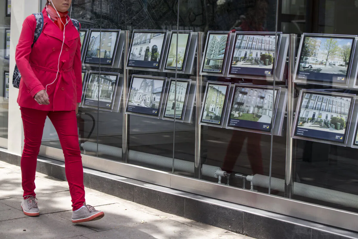 A woman walks past property details displayed in the window of an estate agent in Camden, London, on June 3, 2014. (Oli Scarff/Getty Images)