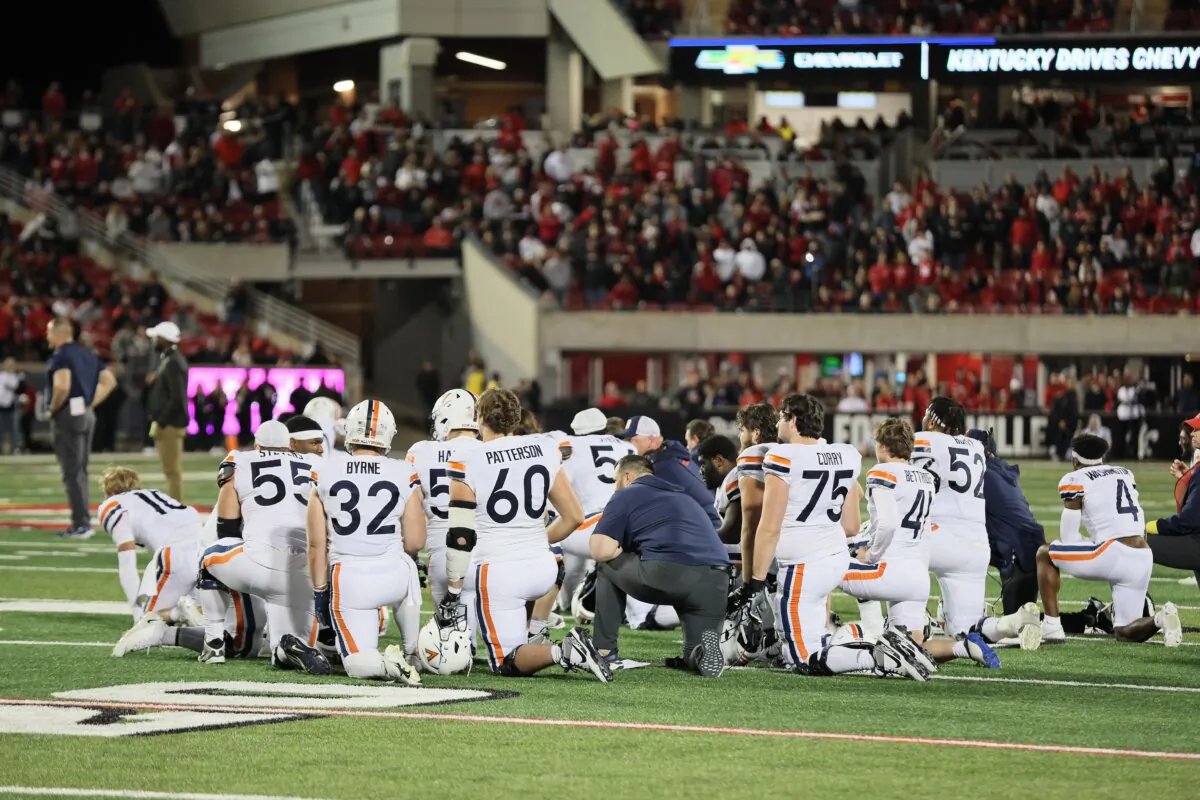 The Virginia Cavaliers kneel while medical staff attend to  Perris Jones (2) after he was injured in the game against the Louisville Cardinals at Cardinal Stadium in Louisville, Ky., on Nov. 9, 2023.. (Andy Lyons/Getty Images)