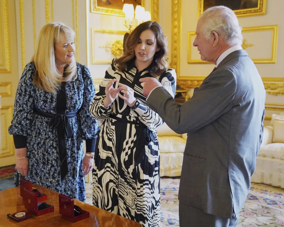 King Charles is presented with the first struck '5 Coronation coin by Royal Mint CEO Anne Jessopp (L) and director Rebecca Morgan (C) at Windsor Castle, Berkshire, on April 13, 2023. (The Canadian Press/AP-Jonathan Brady)