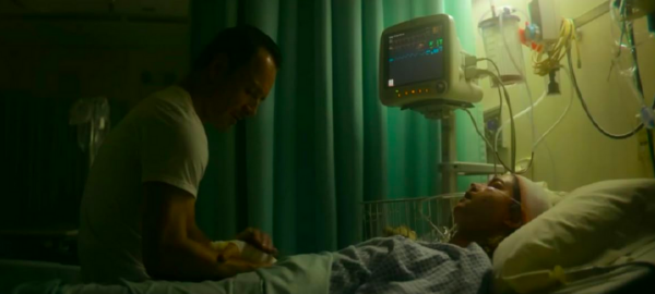 man sitting on hospital bed with woman in THE KILLER