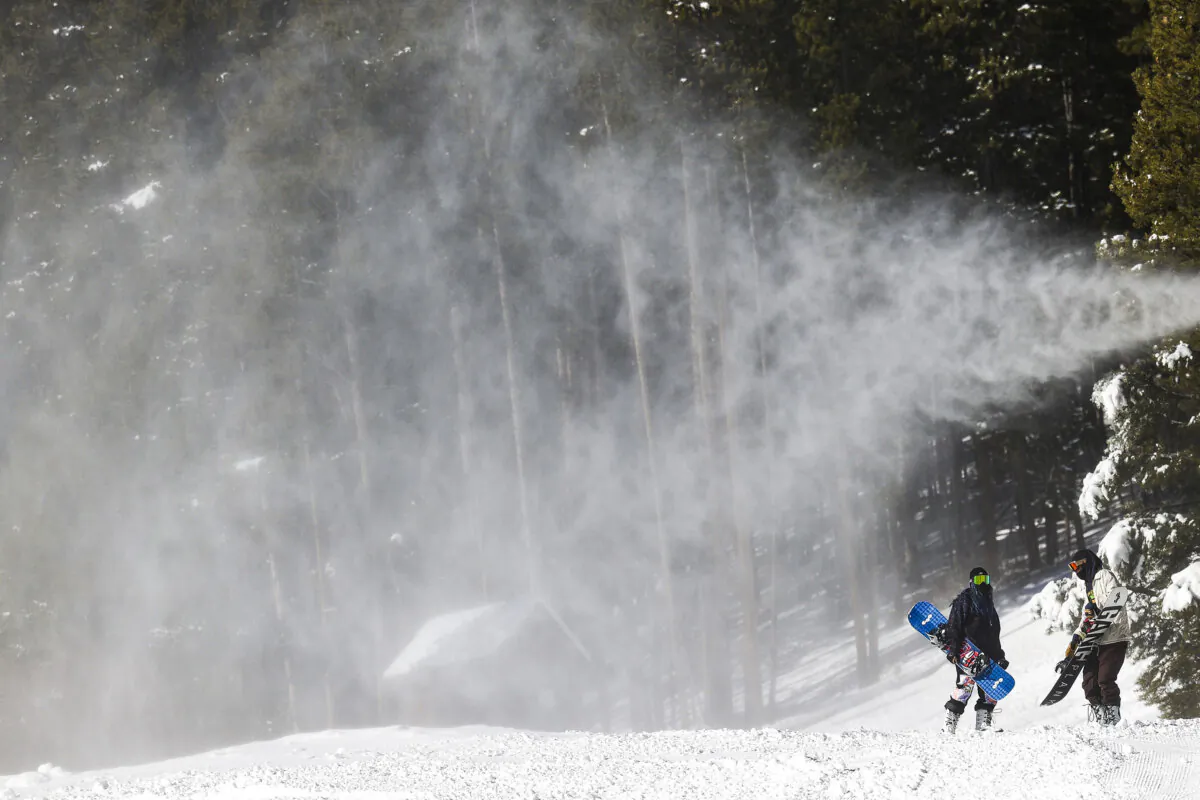 Snowboarders walk under a snow making machine on opening day at Breckenridge Ski Resort on Nov. 13, 2020, in Breckenridge, Colorado. (Michael Ciaglo/Getty Images/TNS)