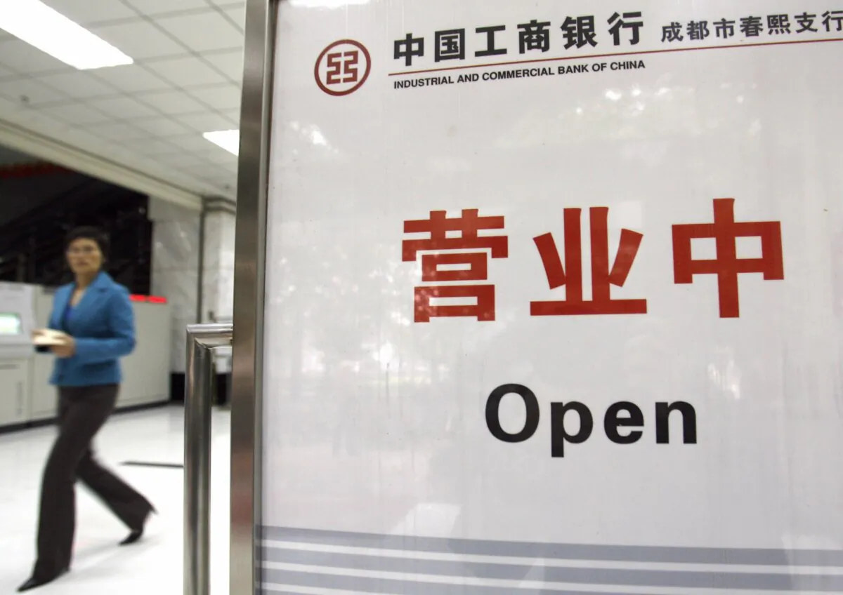 A local customer walks next to a board showing "Open" in a branch office of the Industrial and Commercial Bank of China in Chengdu, on Nov. 3, 2006. (Liu Jin/AFP via Getty Images)
