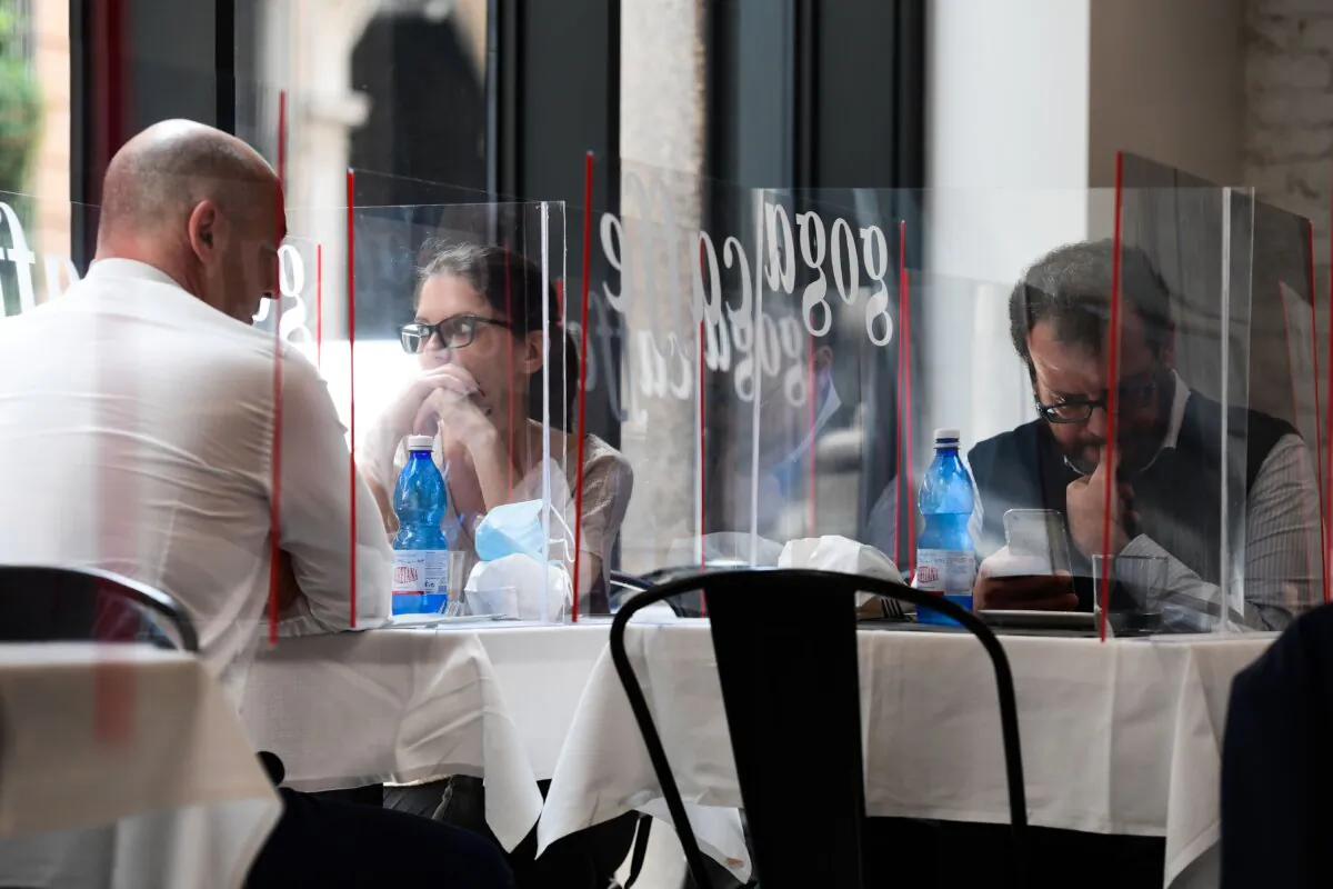 People have lunch at tables partitioned with Plexiglas at the Goga Cafe in central Milan, Italy, on May 18, 2020. (Miguel Medina/AFP via Getty Images)