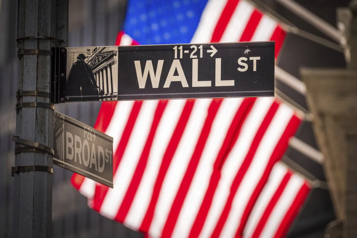 The sun shines through the U.S. flags flying in front of the New York Stock Exchange at the corner of Wall and Broad Streets in New York on Nov. 14, 2023. (J. David Ake/AP Photo)