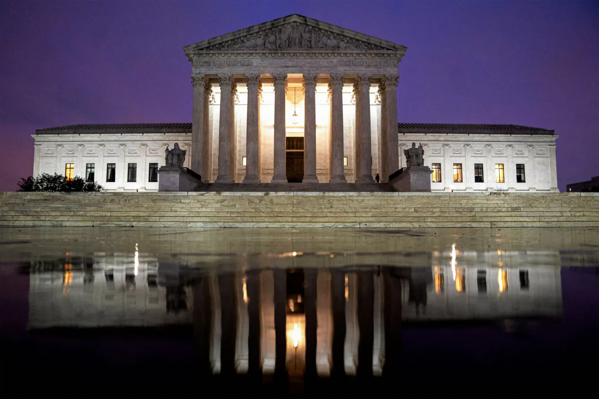 The Supreme Court is reflected in a puddle in Washington on April 5, 2022. (STEFANI REYNOLDS/AFP via Getty Images)