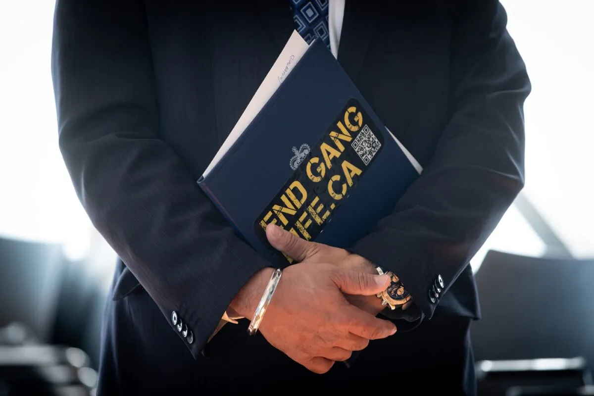 RCMP Assistant Commissioner Manny Mann holds a notebook with an "End Gang Life" sticker on it during a news conference in Burnaby, B.C., on May 10, 2021. (The Canadian Press/Darryl Dyck)