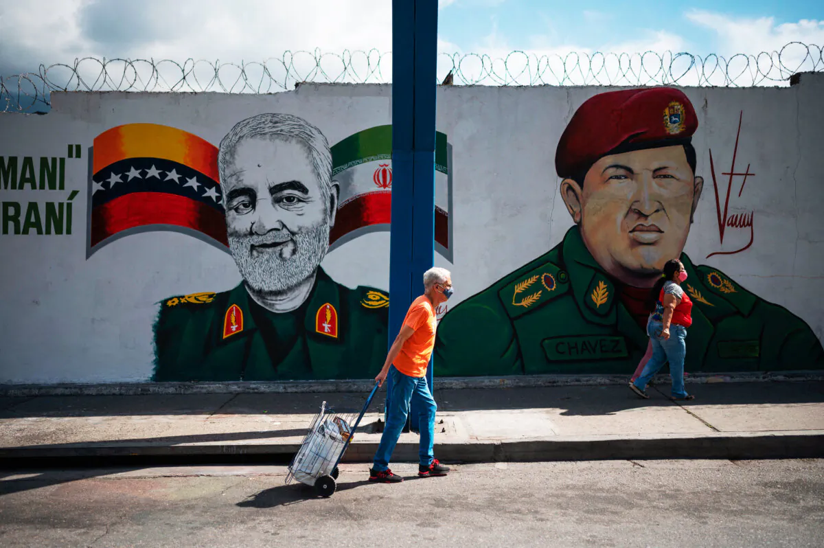 People walk by a mural depicting slain Iranian general Qasem Soleimani (L) alongside Venezuelan President Hugo Chávez (R), in Caracas, Venezuela, on Jan. 4, 2023. (Federico Parra/AFP via Getty Images)