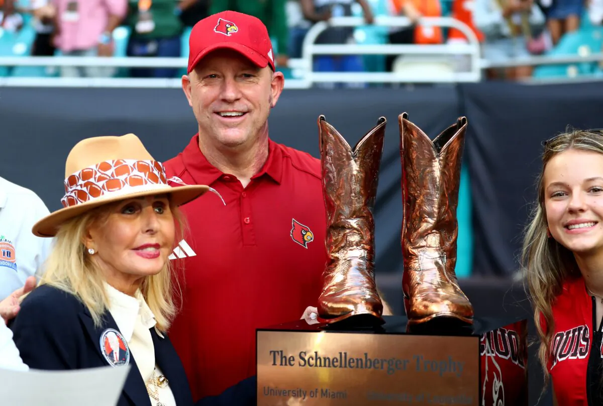 Head coach Jeff Brohm (R) of the Louisville Cardinals receives The Schnellenberger Trophy presented by Beverlee Schnellenberger (L), widow of Howard Schnellenberger—who had coached both programs; in Miami Gardens, Fla., on Nov. 18, 2023. (Megan Briggs/Getty Images)