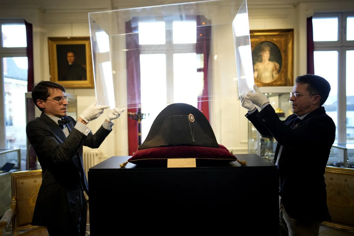 Raphael Pitchal (L) and Jean Christophe Chataignier of Osenat's auction house remove the protection of one of the signature broad, black hats that Napoléon wore when he ruled 19th century France and waged war in Europe at Osenat's auction house in Fontainebleau, south of Paris, on Nov. 17, 2023. (Christophe Ena/AP Photo)