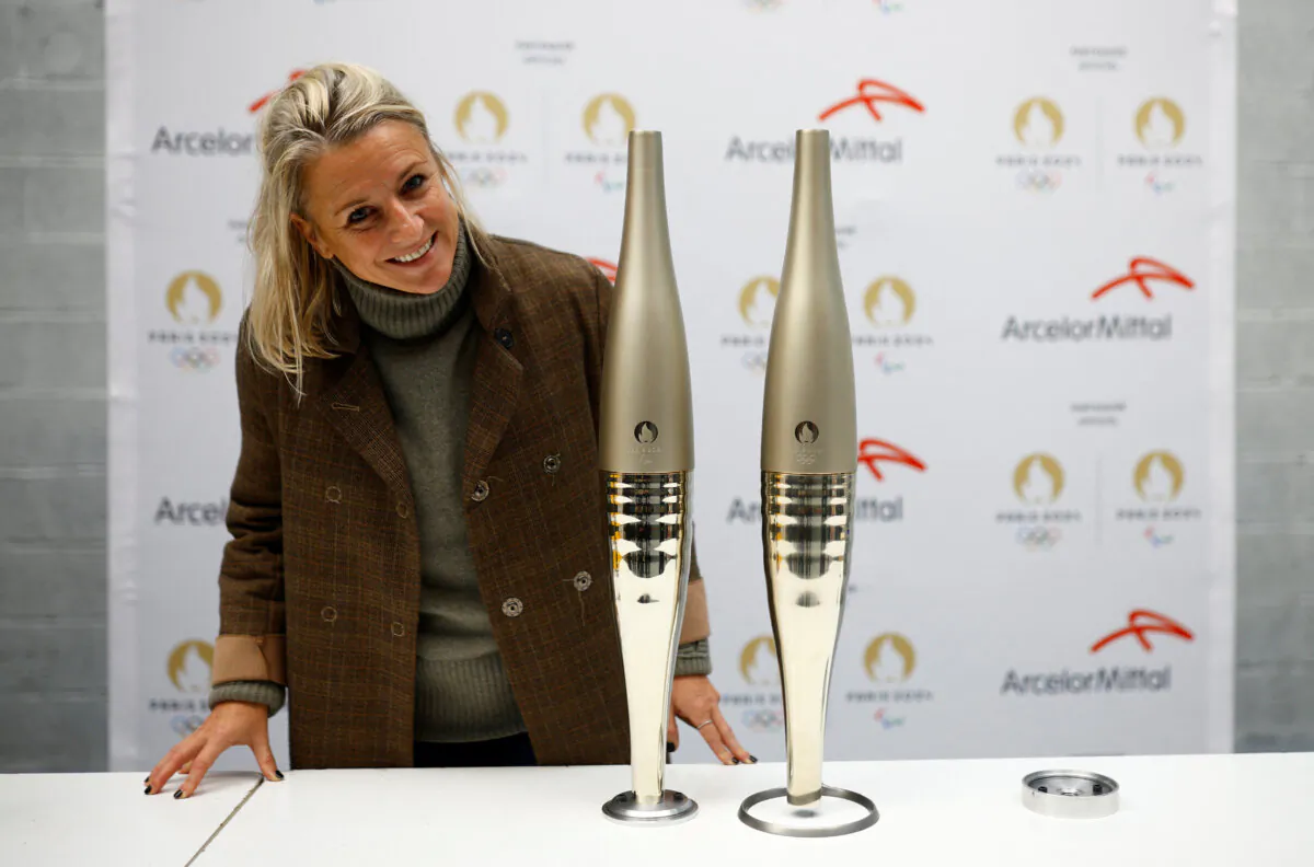 Delphine Moulin, Director of Paris 2024 Ceremonies, poses next to two torches for the Paris 2024 Olympic and Paralympic Games, during a press visit at the Guy Degrenne factory in Vire, France, on Nov. 17, 2023. (Stephane Mahe/Reuters)