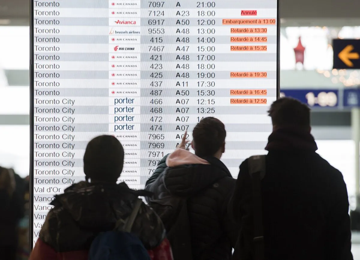 Passengers look at an information board at the departures terminal at Pierre Elliott Trudeau Airport in Montreal, on Dec. 31, 2019. (The Canadian Press/Graham Hughes)