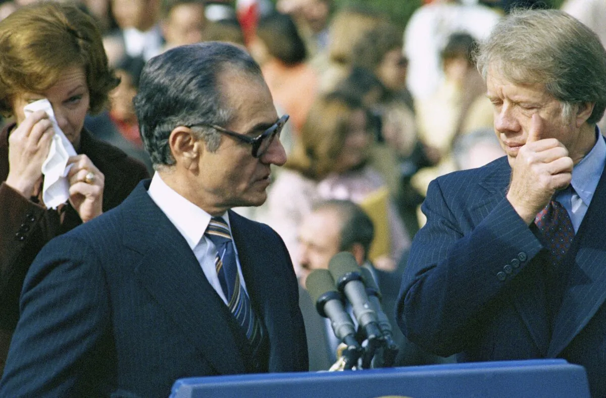 Iran’s Shah Mohammad Reza Pahlavi, U.S. President Jimmy Carter, and first lady Rosalyn Carter react to wafting tear gas as pro- and counter-shah demonstrators clash with police outside of the White House during a ceremony in Washington on Nov. 15, 1977. (AP Photo/File)