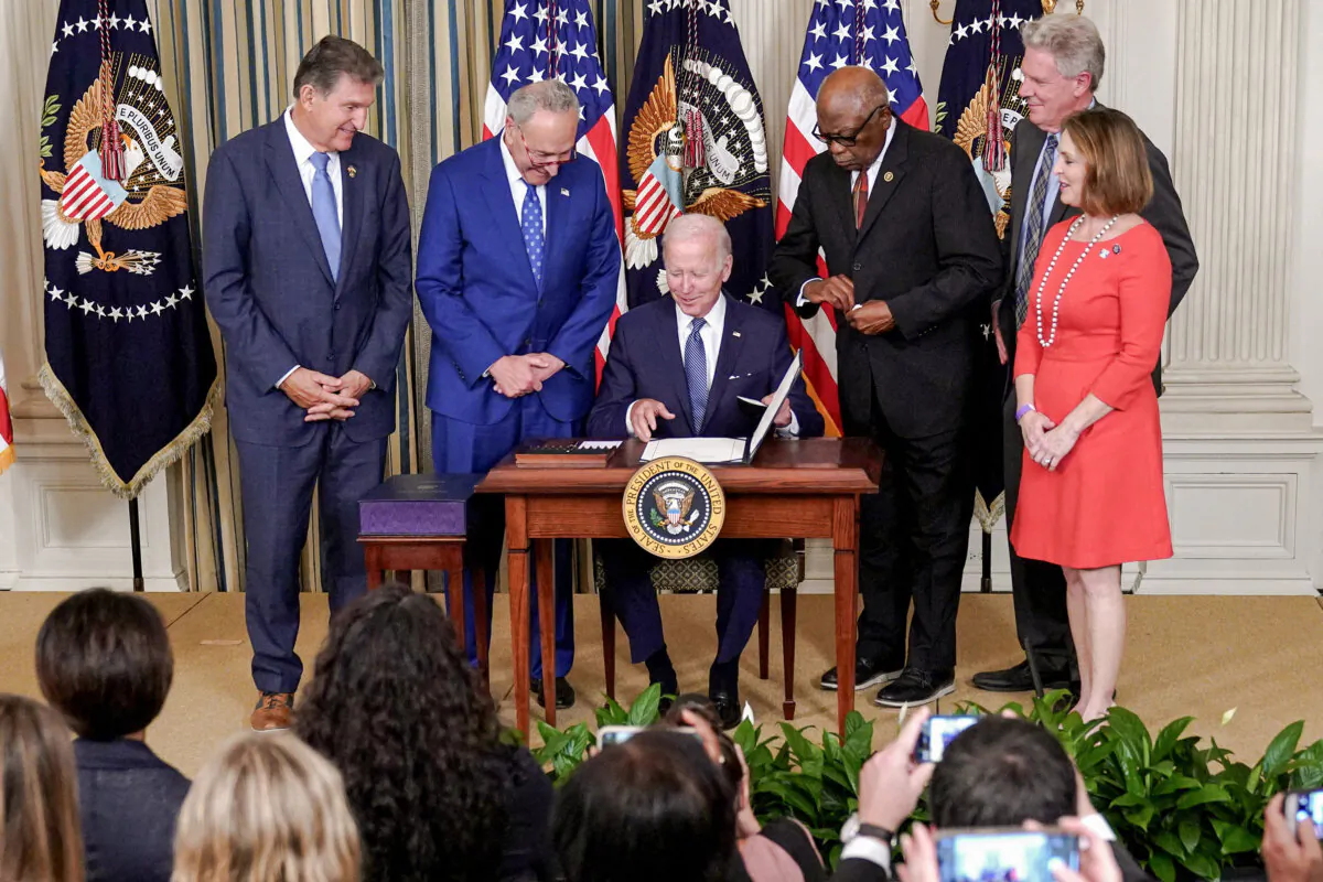 President Joe Biden (C) smiles after signing H.R. 5376, the Inflation Reduction Act of 2022, in the State Dining Room of the White House in Washington on Aug. 16, 2022. (Mandel Ngan/AFP via Getty Images)