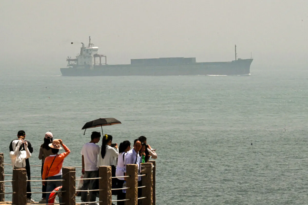  A cargo ship sails in the Taiwan Strait as tourists watch from a lighthouse on Pingtan island, the closest point in China to Taiwan, in southeast China's Fujian Province on April 16, 2023. (Greg Baker/AFP via Getty Images)