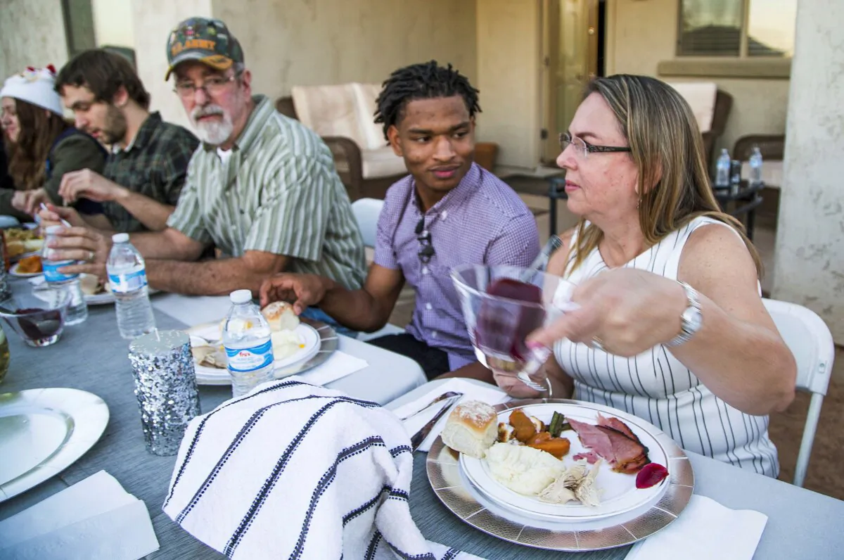 Jamal Hinton, (C), Wanda Dench, (R), and her family and friends, have Thanksgiving dinner at Dench's home, in Mesa, Ariz., on Nov. 24, 2016. (Tom Tingle/The Arizona Republic via AP)