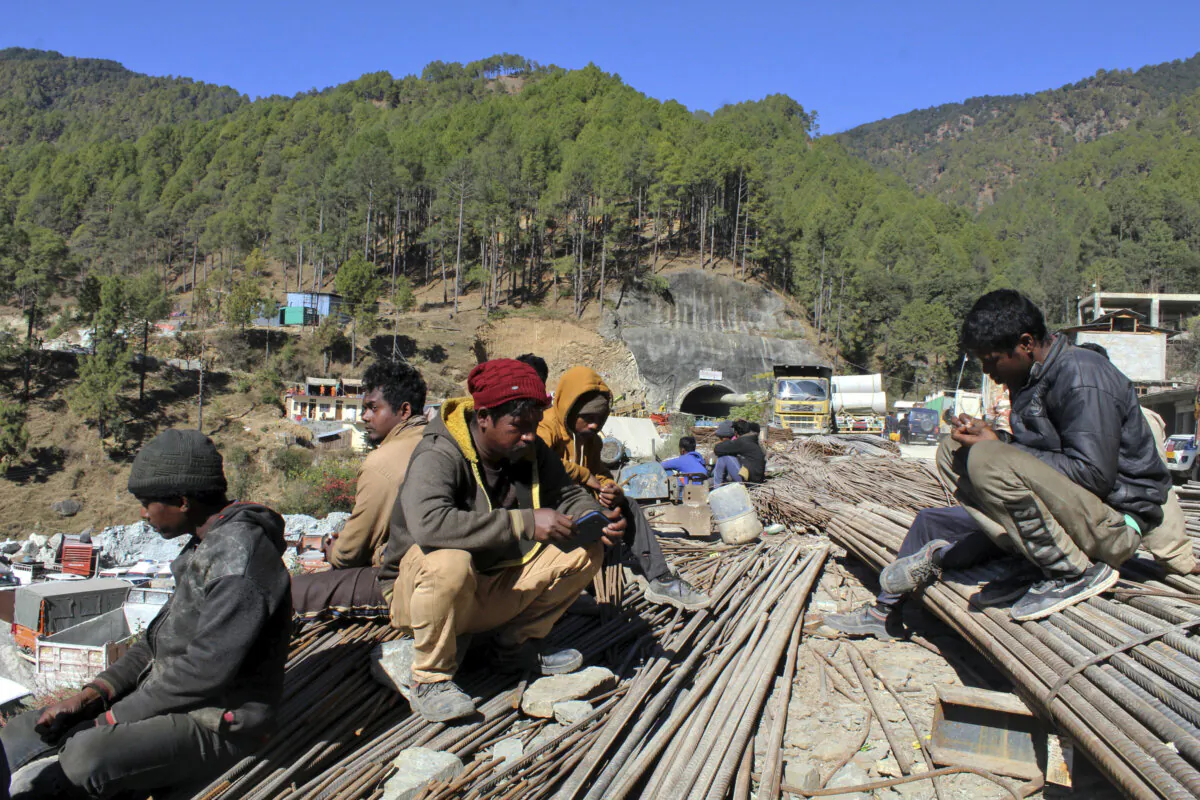 People wait by the site of an under-construction road tunnel that collapsed trapping 41 workers in Silkyara in the northern Indian state of Uttarakhand on Nov. 22, 2023. (AP Photo)