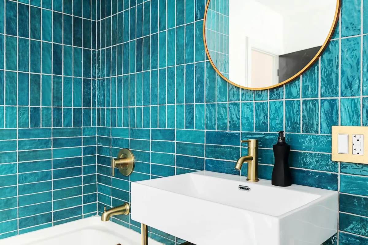Blue and green tile bathroom with gold fixtures and mirror. (Fio Creative/Shutterstock)