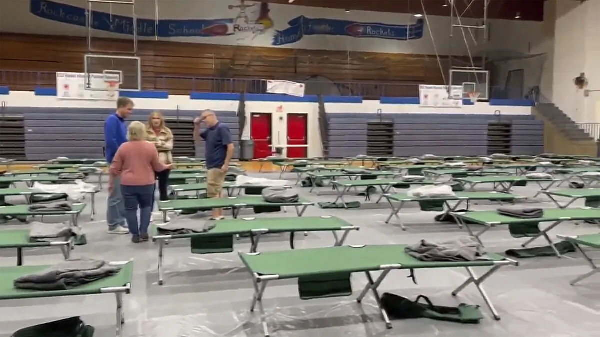 People help arrange cots at Rockcastle Middle School, being used as an evacuation center, in Mt Vernon, Ky., on Nov. 22, 2023. (WTVQ via AP)