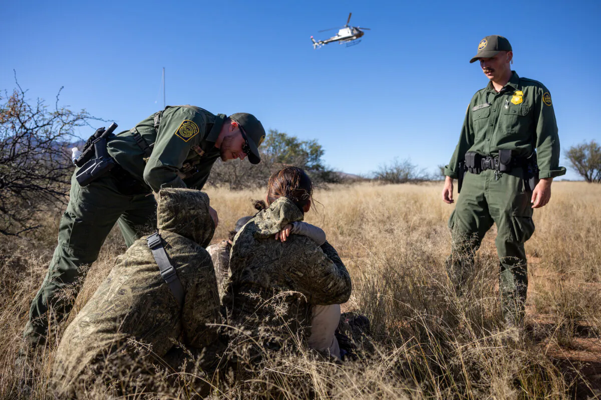 U.S. Border Patrol agents detain a camouflaged family from Mexico after they had illegally crossed the U.S.–Mexico border near Naco, Ariz., on Nov. 4, 2022. (John Moore/Getty Images)