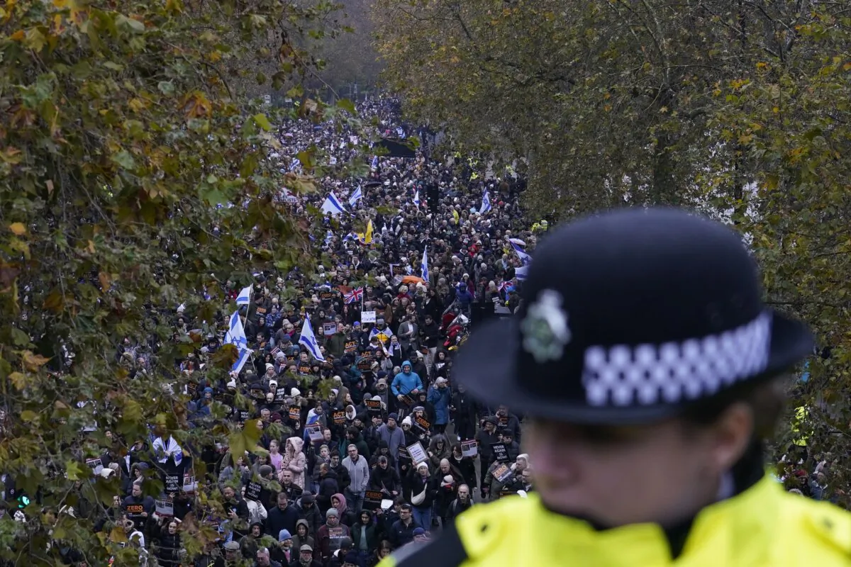 A policewoman stand guard on a bridge as an anti-Semitism demonstration with protesters holding placards flags and banners, including the flag of Israel, takes place in London on Nov. 26, 2023. (Alberto Pezzali/AP Photo)