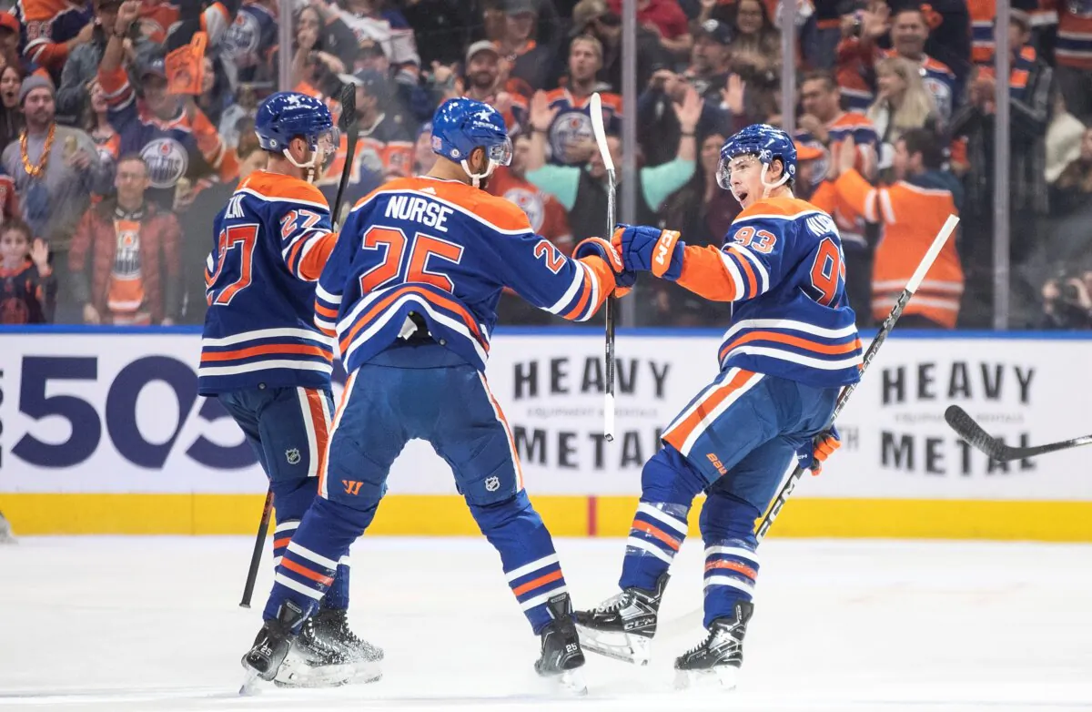Edmonton Oilers' Brett Kulak (27), Darnell Nurse (25) and Ryan Nugent-Hopkins (93) celebrate after a goal against the Anaheim Ducks during first-period NHL hockey game action in Edmonton, Alberta, Canada, on Nov. 26, 2023. (Jason Franson/The Canadian Press via AP)
