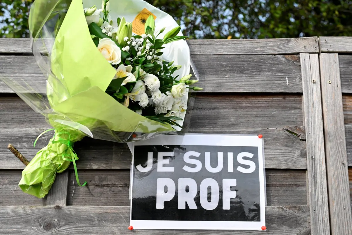 Flowers next to a placard reading "I am a teacher" in tribute to Samuel Paty, it pictured near the Bois d'Aulne school in Conflans-Sainte-Honorine, outside Paris on Oct. 16, 2023. (Bertrand Guay, Pool via AP)