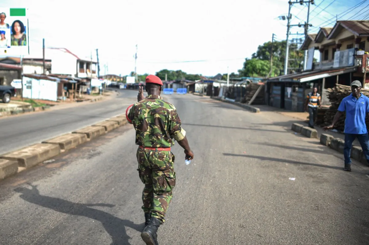 A soldier with the Sierra Leonean military police greets and man along an empty road in Freetown on Nov. 26, 2023. A military armory in Sierra Leone's capital Freetown came under attack on Sunday, the government said, as it imposed an immediate national curfew. (Saidu Bah/AFP via Getty Images)