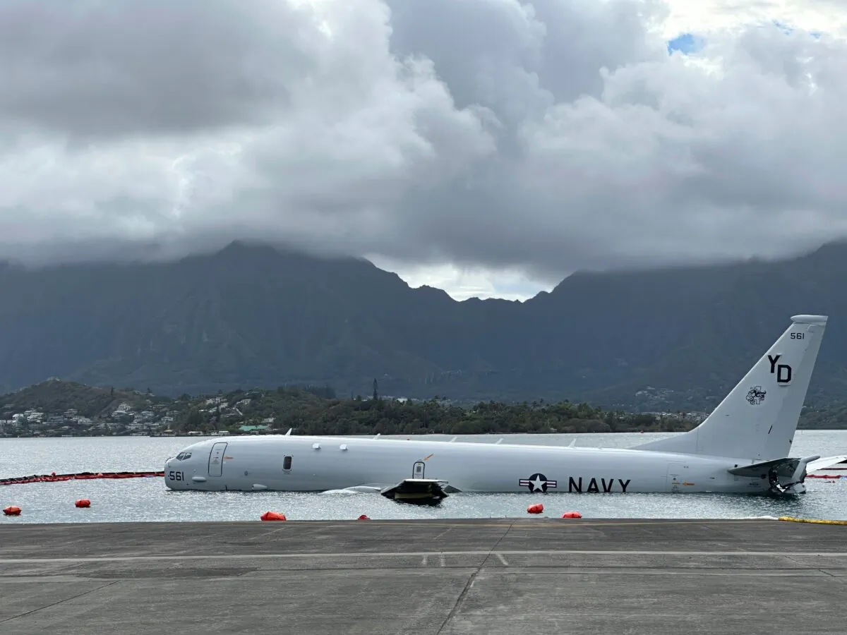 A Navy P-8A plane that overshot a runway at Marine Corps Base Hawaii and landed in shallow water offshore sits on a reef and sand in Kaneohe Bay, Hawaii, on Nov. 27, 2023. (Audrey McAvoy/AP Photo)