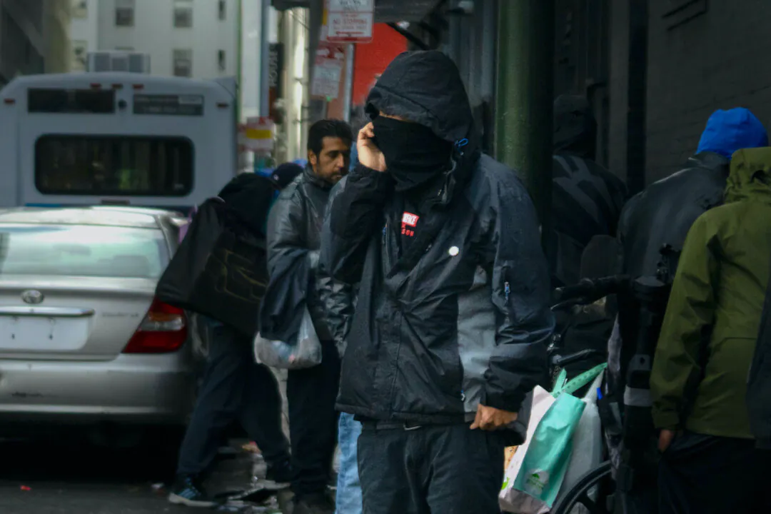 An alleged drug dealer stands near a row of drug addicts in San Francisco on Feb. 23, 2023. (John Fredricks/The Epoch Times)