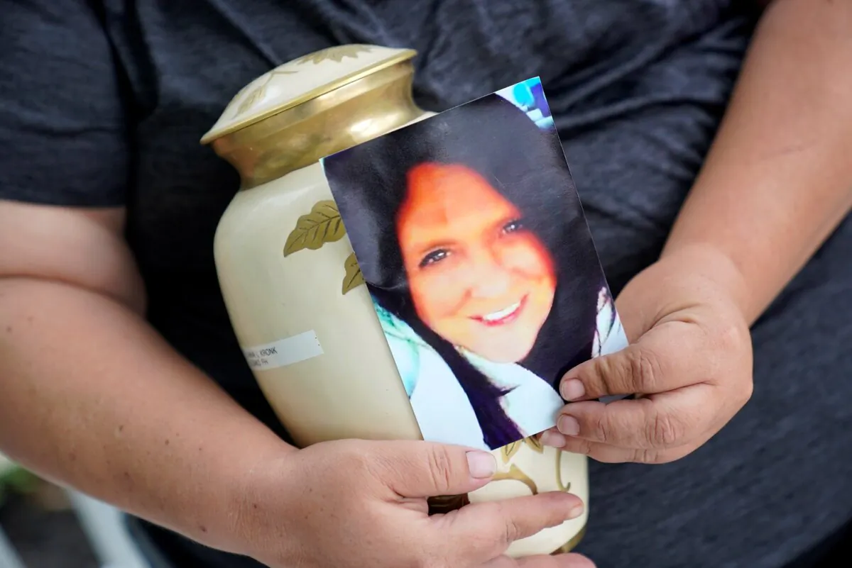 Kelly Titchenell sits on her porch, also holding a photo of her mother Diania Kronk, and an urn containing her mother's ashes in Mather, Pa., on July 7, 2022. (Gene J. Puskar/AP Photo)