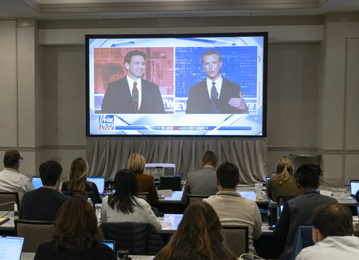 Florida Governor and Republican presidential hopeful Ron DeSantis (L) and California Governor Gavin Newsom (R) appear on screen from the press room during a debate held by Fox News, in Alpharetta, Ga., on Nov. 30, 2023. (Christian Monterrosa/AFP via Getty Images)